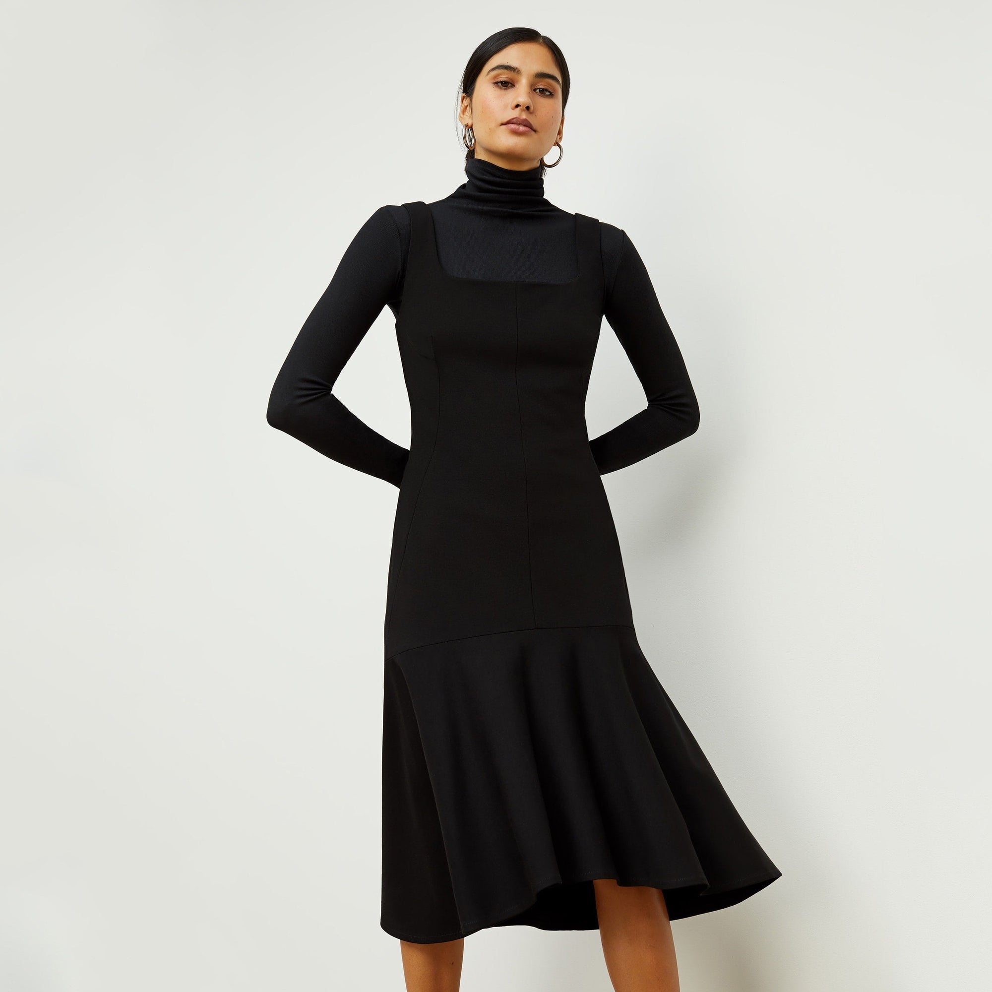 Front image of a woman standing wearing the axam top in black | Exclude
