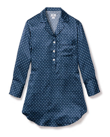 The Womens Silk Nightshirt in Midnight Foulard by Petite Plume is a perfect nightshirt. It boasts a blue patterned design with circular shapes in various shades of blue and white, a half-button placket with four buttons, and a single chest pocket.