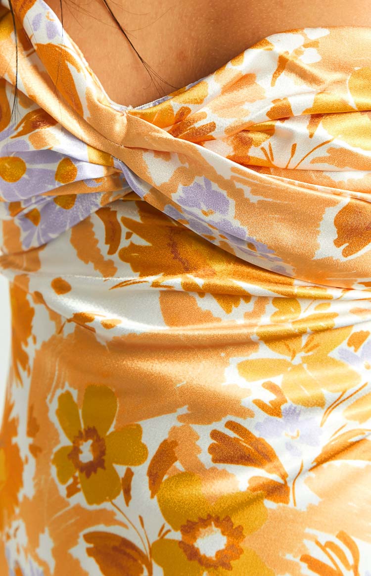 Close-up of the twisted neckline detail and orange, white, and purple floral print on a satin maxi dress