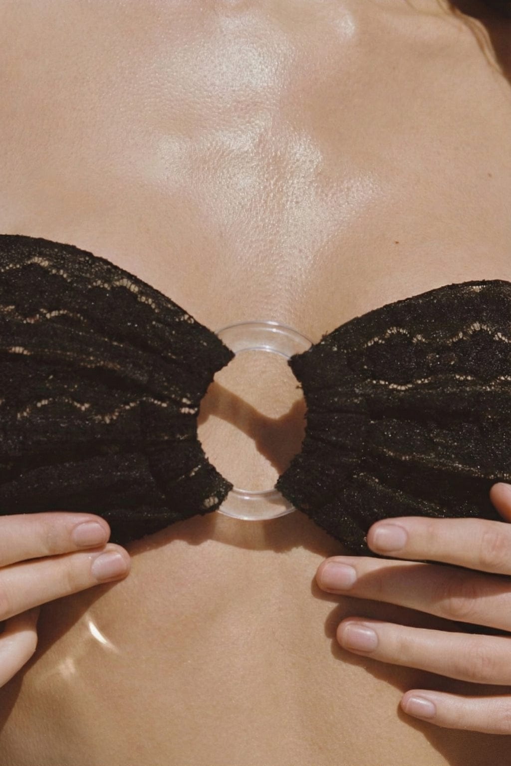 Black lace bandeau bikini top with daisy pattern and clear center clasp, worn on model.