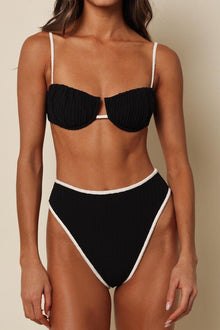 Black terry rib bikini top with cream-colored binding and spaghetti straps, featuring petal-shaped cups.