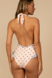 Cream one-piece swimsuit with cherry print, halter neckline, ruffle edges, and striped trim details, shown from back view.