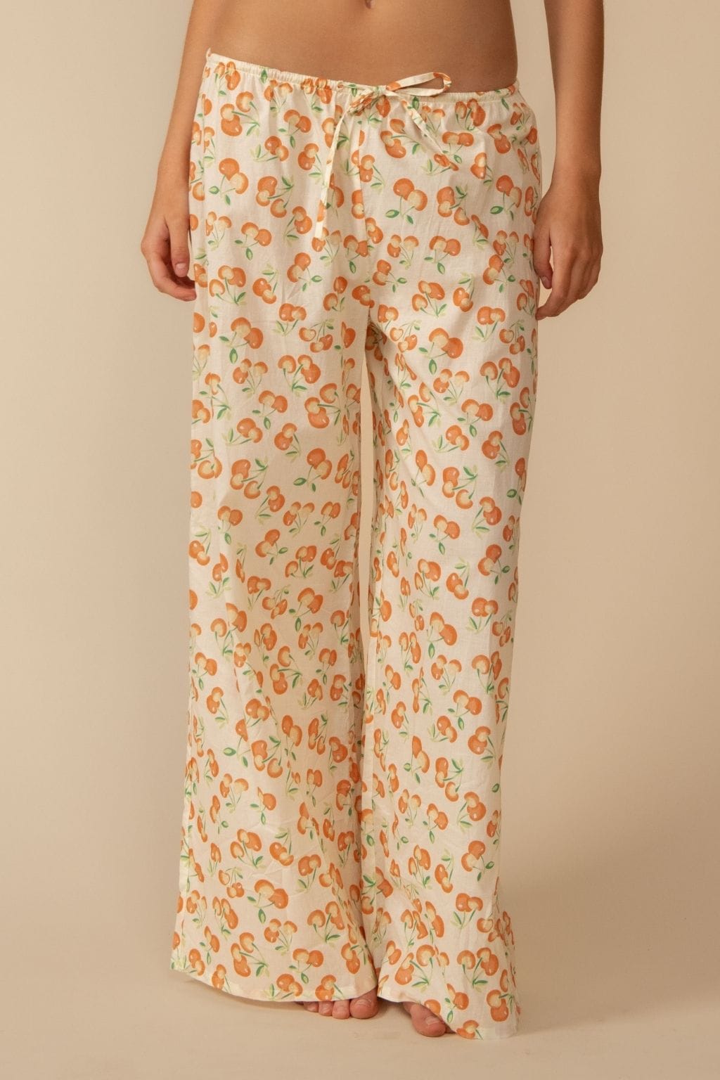Wide-leg pants with cherry print and drawstring waist in cream and orange tones.