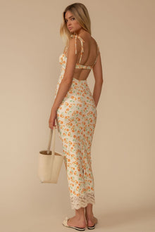 Cream slip dress with orange floral print, lace trim at hem, tie-back detail, worn with cream tote bag.