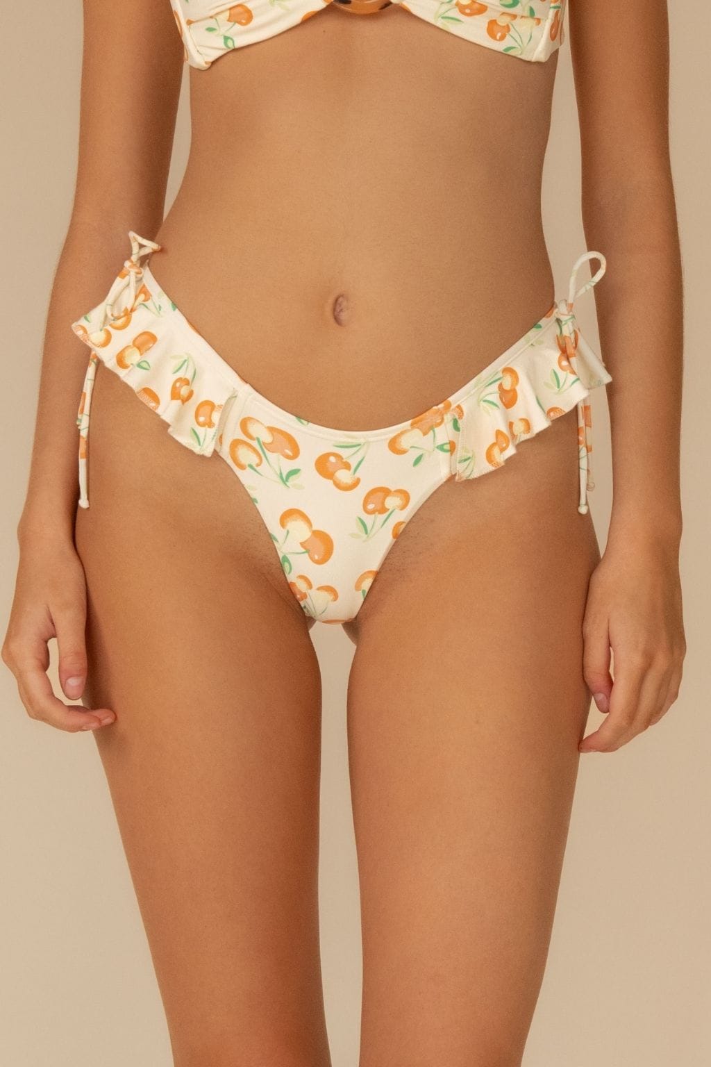 Cream bikini bottom with orange cherry print and ruffled edges, tie-side closures.