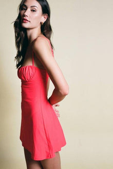 Red slip dress with thin straps and ruched bust detail, knee-length A-line silhouette.