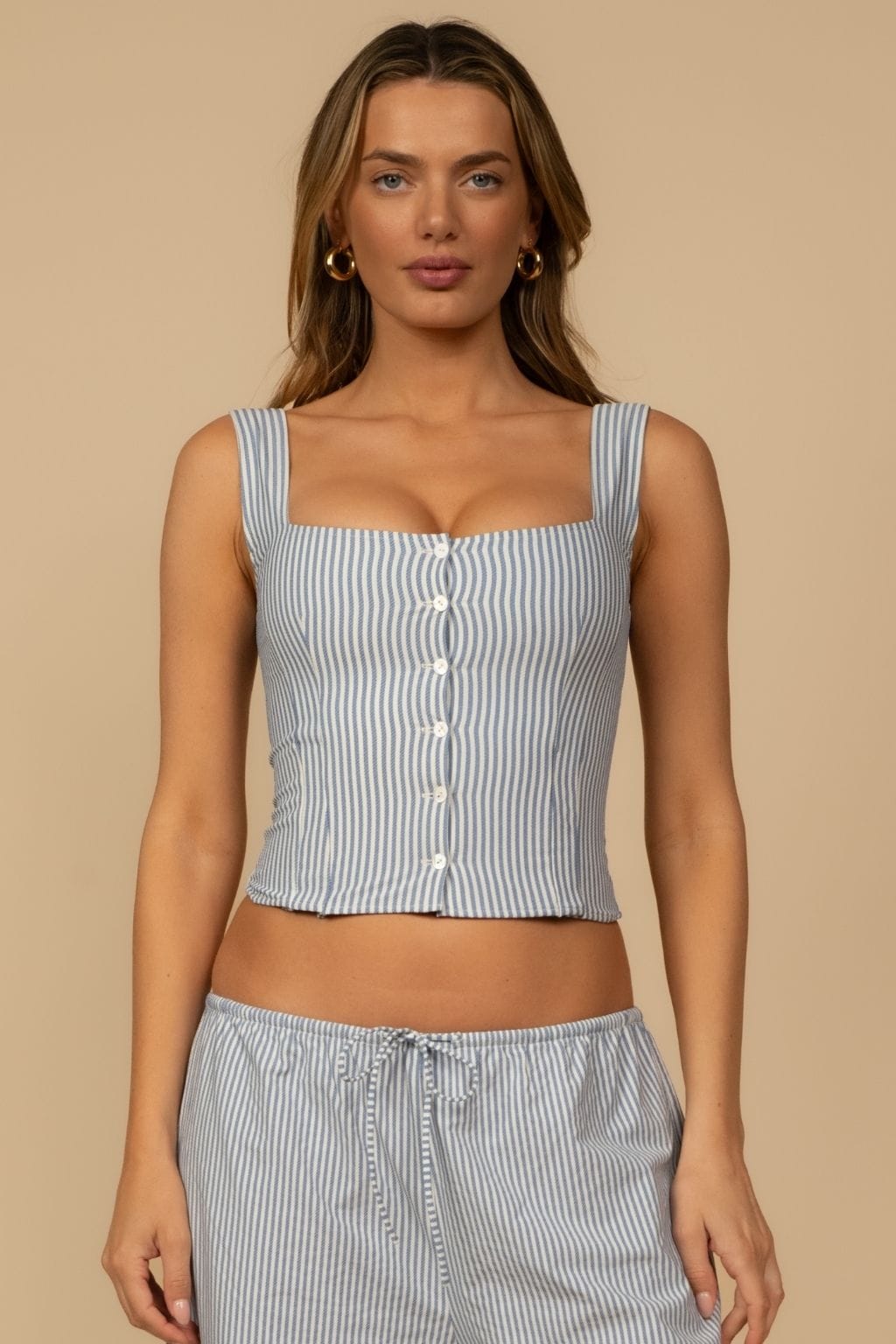 Blue and white striped sleeveless tank top with square neckline and white button front closure.