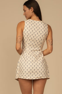 Sleeveless cream dress with small dark floral print throughout, shown from back view on model.