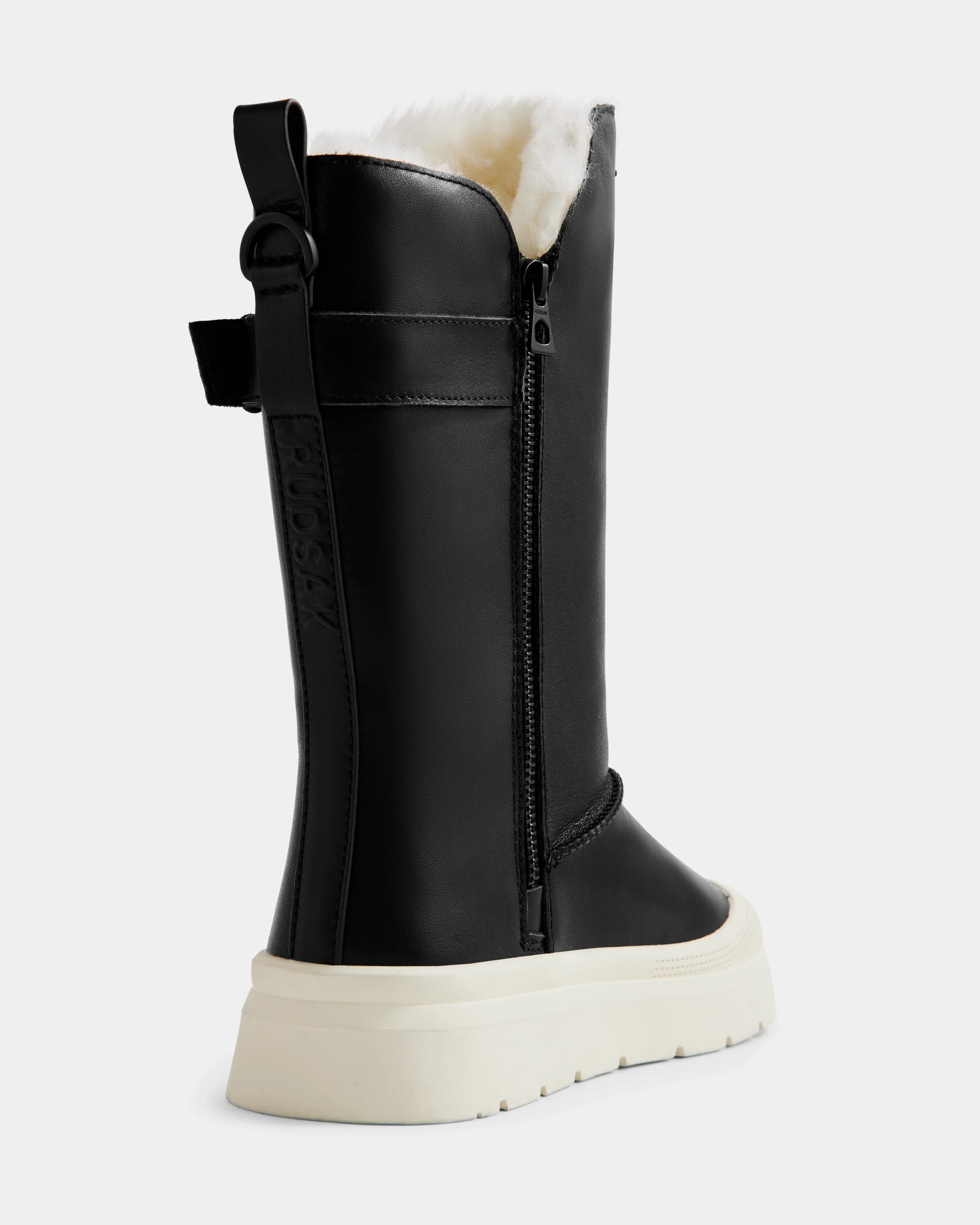 The Rudsak KLAIR L - L225519 Black is a women’s black mid-calf boot with white chunky sole, side zipper, back pull tab, and cozy exposed faux fur lining—stylish leather boots ideal for urban adventures.