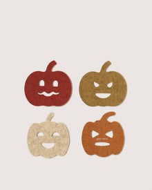 Four Graf Lantz felt coasters shaped like jack-o'-lanterns, each in red, brown, cream, or orange with unique faces, arranged in a grid on a light background.
