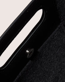 A graf lantz dark gray Merino Wool rectangular tote bag features a cutout handle and small circular perforations on the lower half. Set against a light neutral background, it highlights the minimalist design.