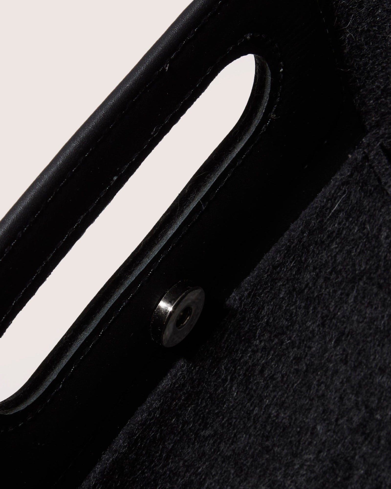 A graf lantz dark gray Merino Wool rectangular tote bag features a cutout handle and small circular perforations on the lower half. Set against a light neutral background, it highlights the minimalist design.
