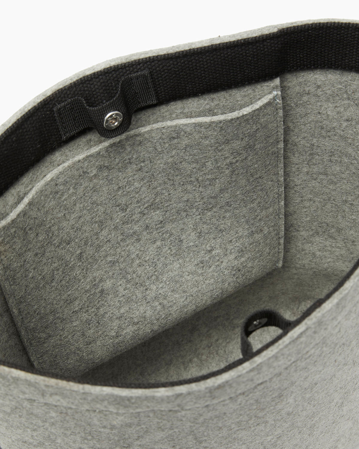 The graf lantz grey felt tote bag is made from sustainable materials, featuring black trim and a small front interior pocket for functionality. It has a button clasp to secure the top, and its soft fabric makes it perfect for daily use.