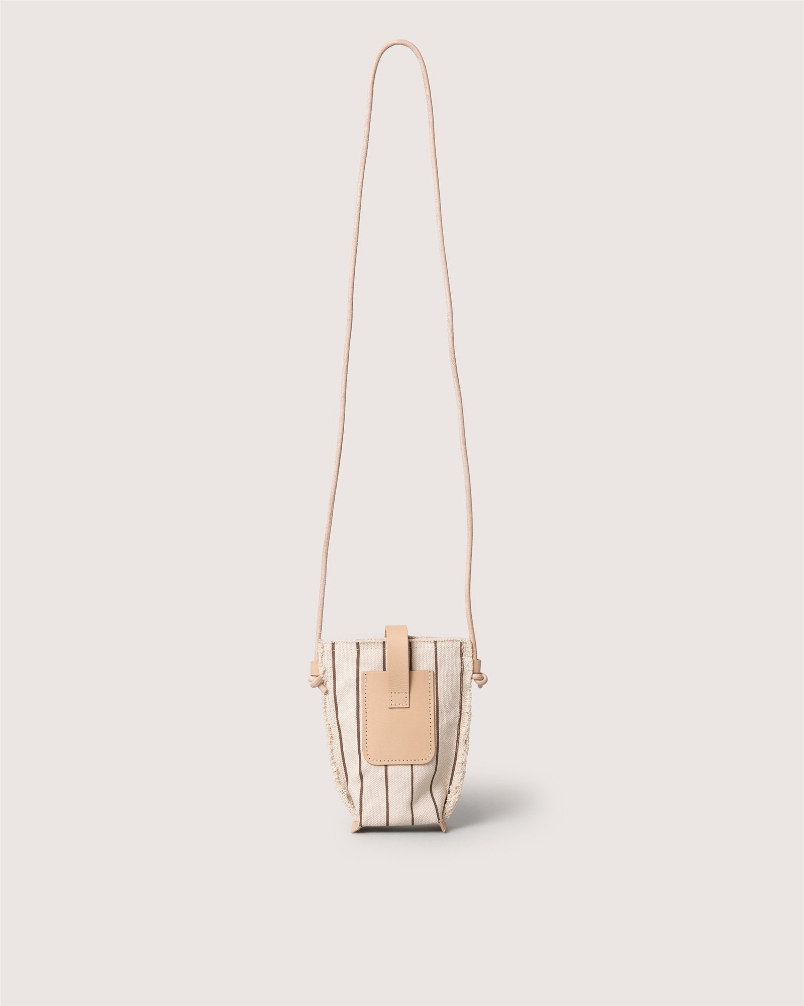 A compact crossbody, the Graf Lantz Hana Canvas Phone Crossbody is a small beige bag with vertical black stripes, a tan leather strap, and a tan leather flap closure—perfect for hands-free style against a plain white background.