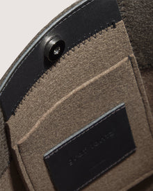 Close-up of the inside of a Graf Lantz felt bag with a snap button closure, internal pocket, and black leather patch with embossed text.