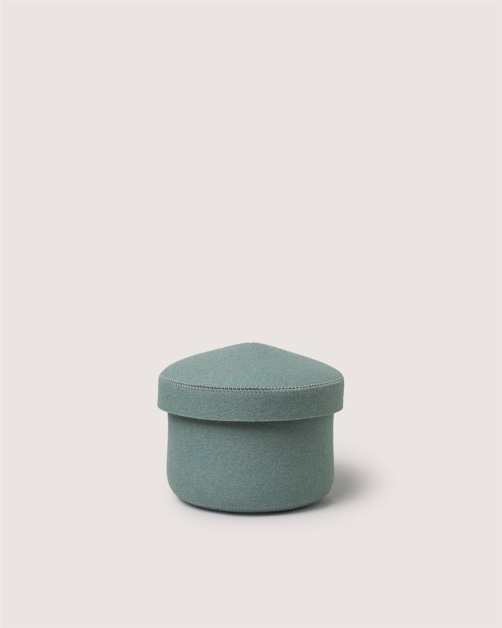 A small, light green Merino wool bin by Graf Lantz, featuring a rounded triangular lid. This sustainable organizer is displayed against a plain off-white background.