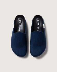 A pair of dark blue slip-on slippers from graf lantz, featuring black insoles with white text and a recycled rubber sole, viewed from above against a light gray background.