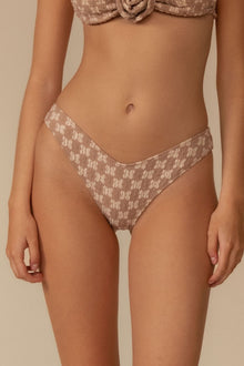 Beige lace bikini bottom with zig-zag stitch pattern and low-rise waistband on model.