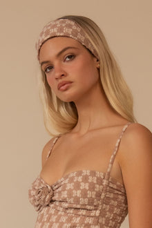 Wide lace headband in dusty rose worn across the forehead on a model with long blonde hair.