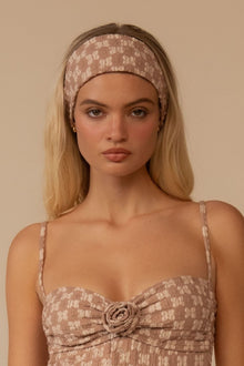 Wide lace headband in dusty rose with floral pattern worn on forehead.