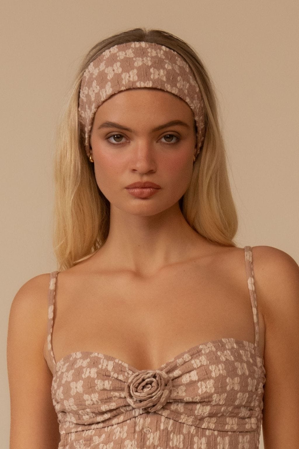 Wide lace headband in dusty rose with floral pattern worn on forehead.