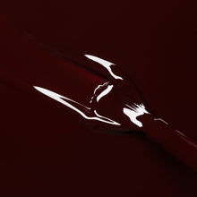 A close-up image of glossy, deep red liquid lipstick being applied to a surface, with the shape of lips visible in the shiny texture.