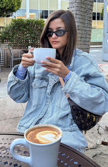 Light wash oversized denim jacket with button-flap chest pockets, a full button placket, and wide long sleeves