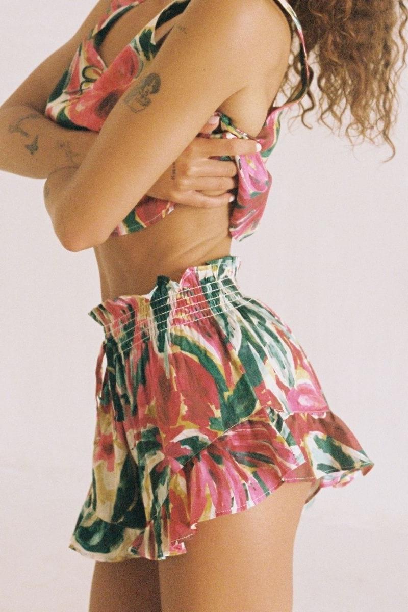 Floral print mini shorts with pink, red, green and cream flowers, featuring a smocked waistband.