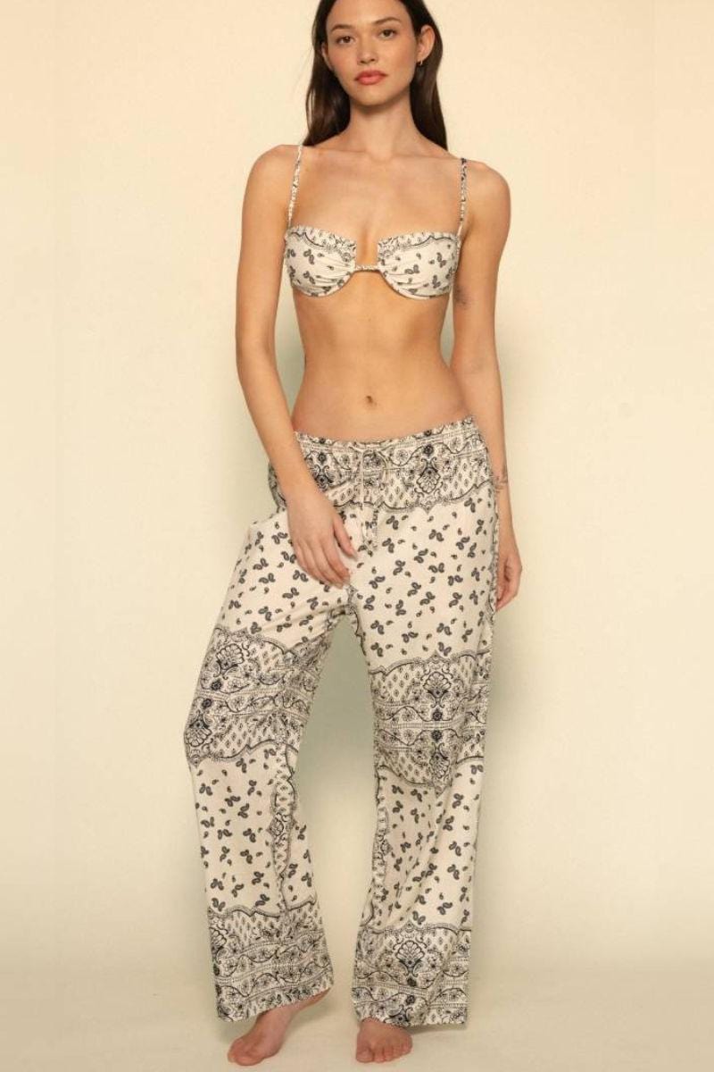 Wide leg pant in cream with small floral and bandana print pattern throughout, worn with matching bandeau bikini top.