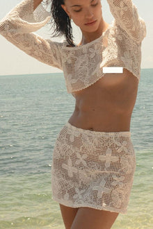 Cream lace micro skirt with floral openwork pattern worn at the beach.