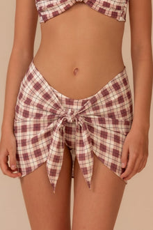 Maroon and cream plaid sarong with tie-front closure worn at waist level.