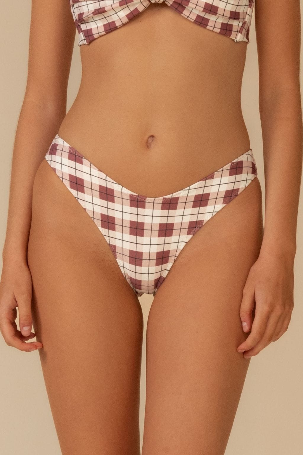 Maroon and cream plaid bikini bottom with zig-zag stitching on waistband, displayed on model.