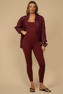 Maroon long onesie with matching button-up shirt jacket and ruffled cuffs, shown on model with black slides.