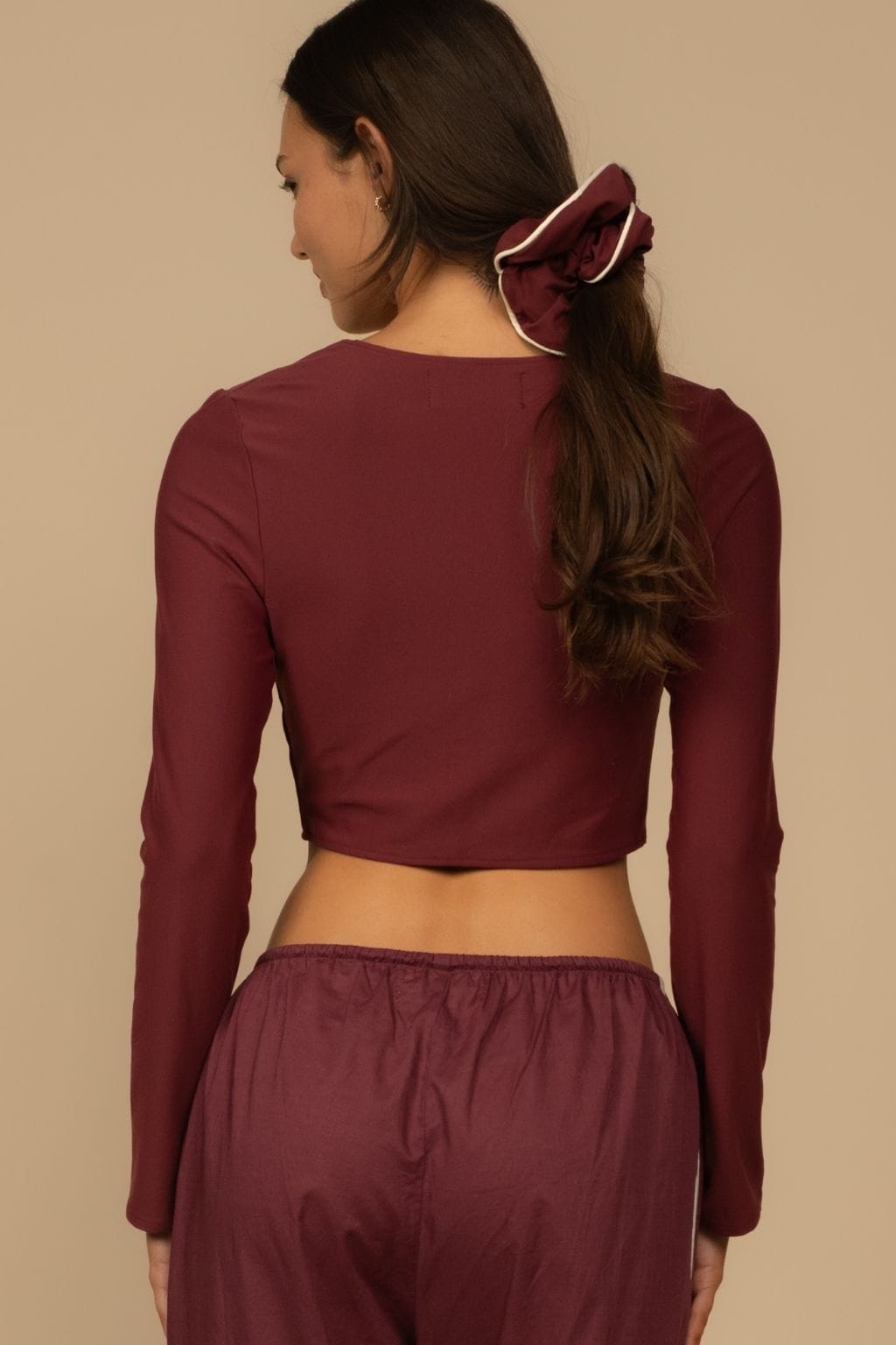 Maroon cropped cardigan with long sleeves shown from back on model wearing matching bottoms.