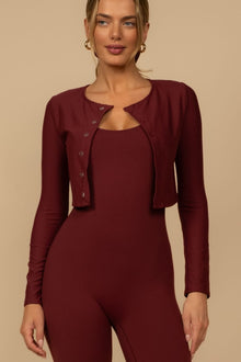 Maroon cropped cardigan with button front worn over matching long-sleeve top.