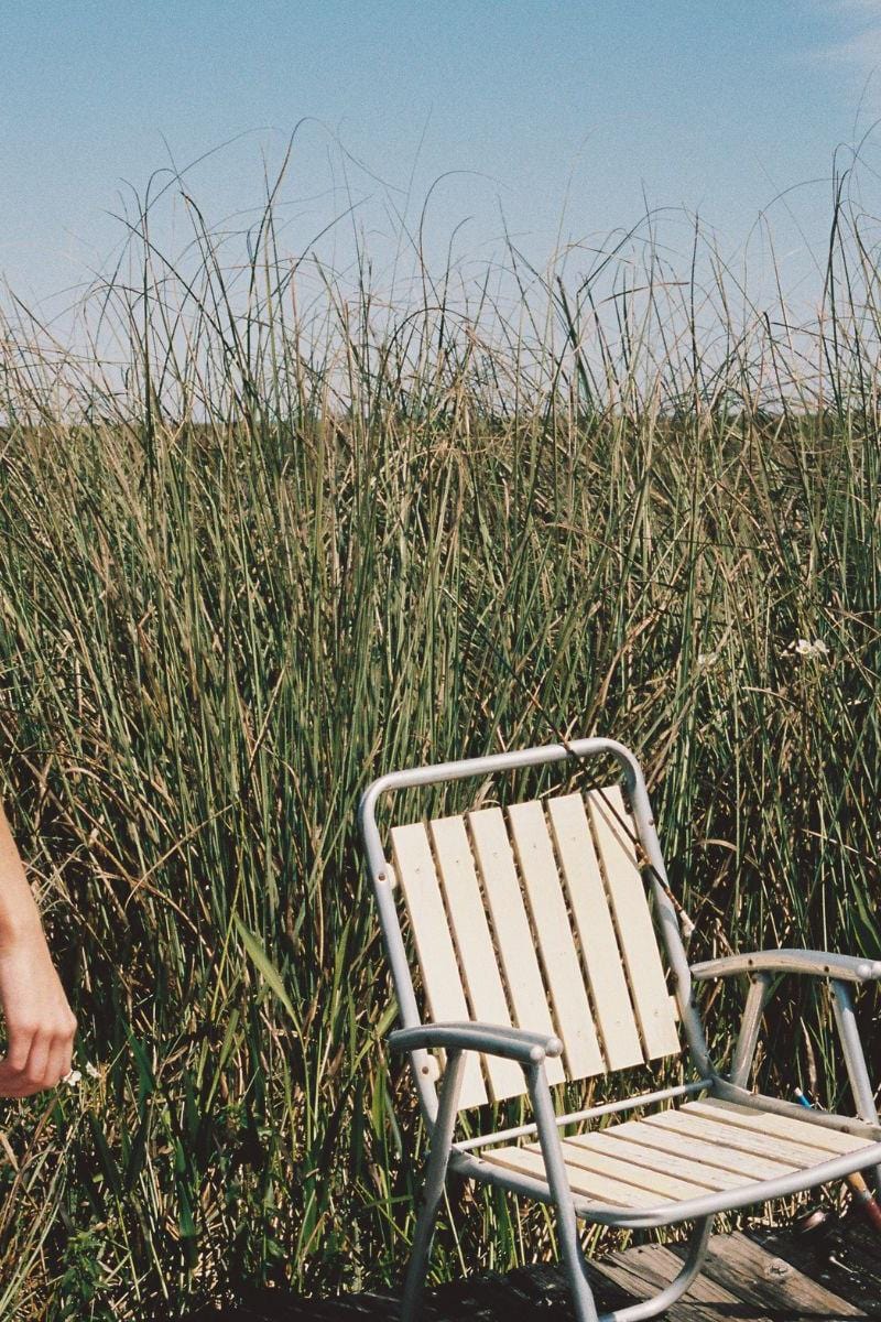 Oat and terracotta bikini bottom with bound edges, displayed on model in marshland setting.
