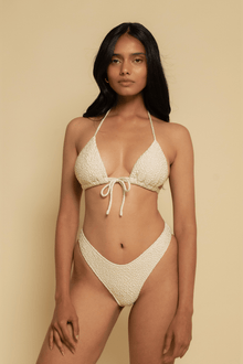 Oat-colored bikini bottom with textured fabric and zig-zag stitching details on high-cut legs.