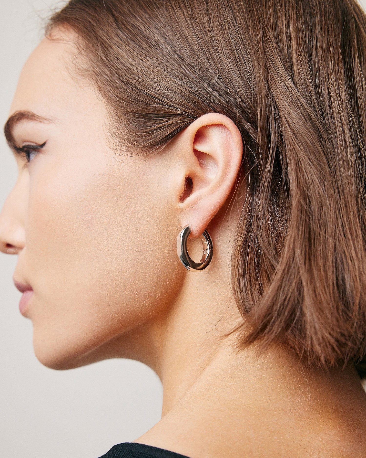 Model wearing huggie earring. 