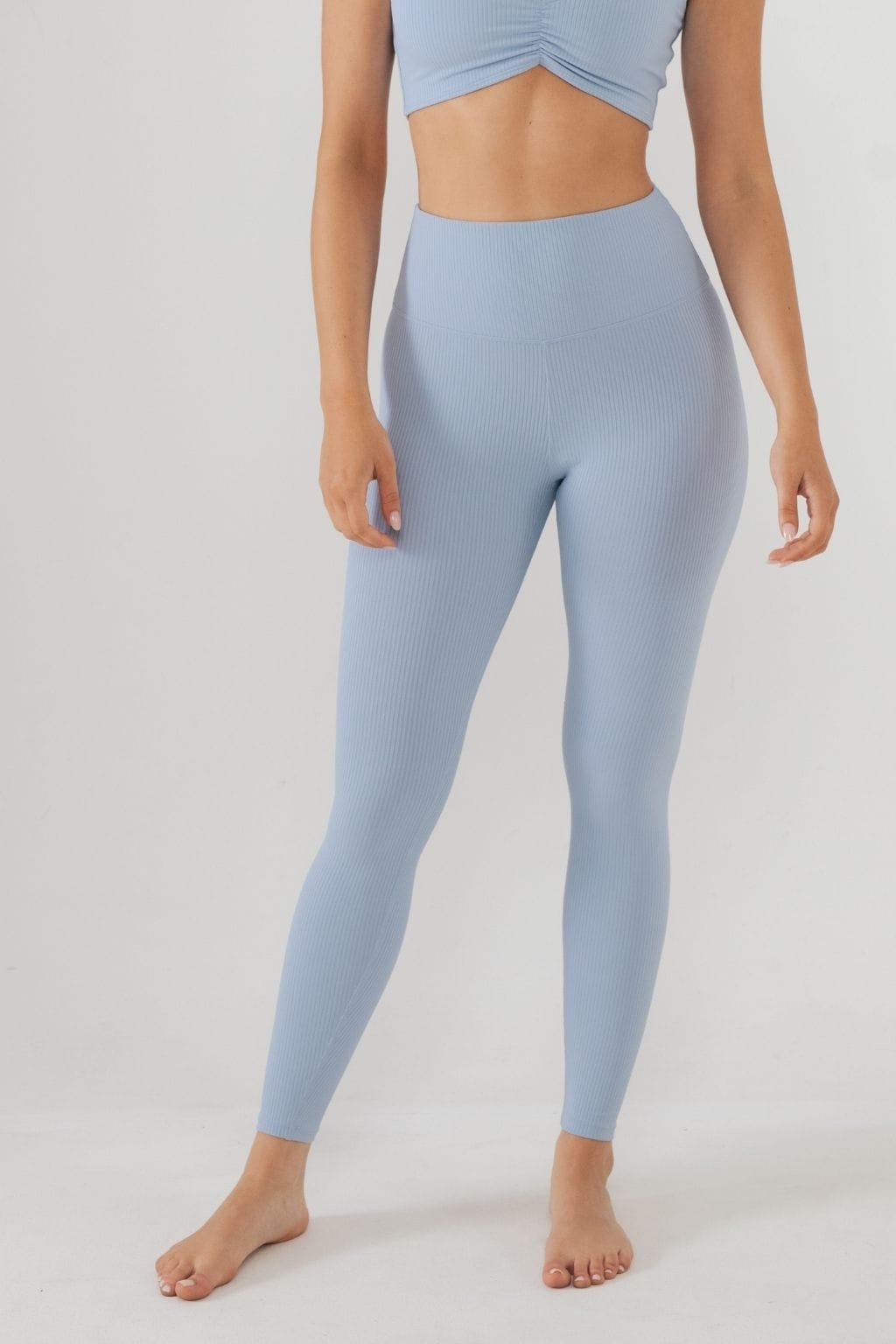 Pale blue ribbed leggings with high waist and cropped top on model against white background.