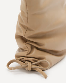 Close-up of a beige drawstring bag on a white background