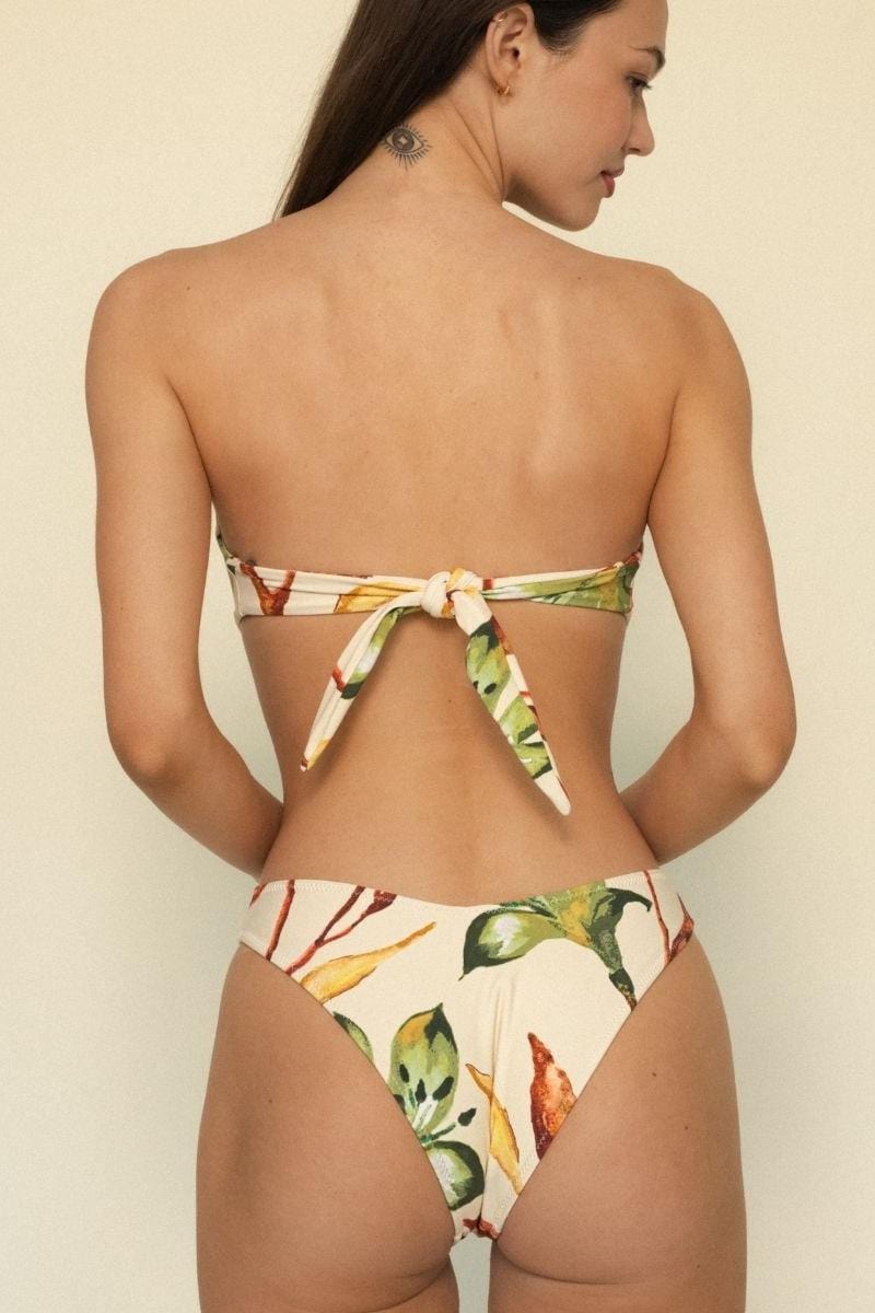 Bandeau bikini top with floral print in cream, green, yellow, and red tones, featuring tie closure at back.