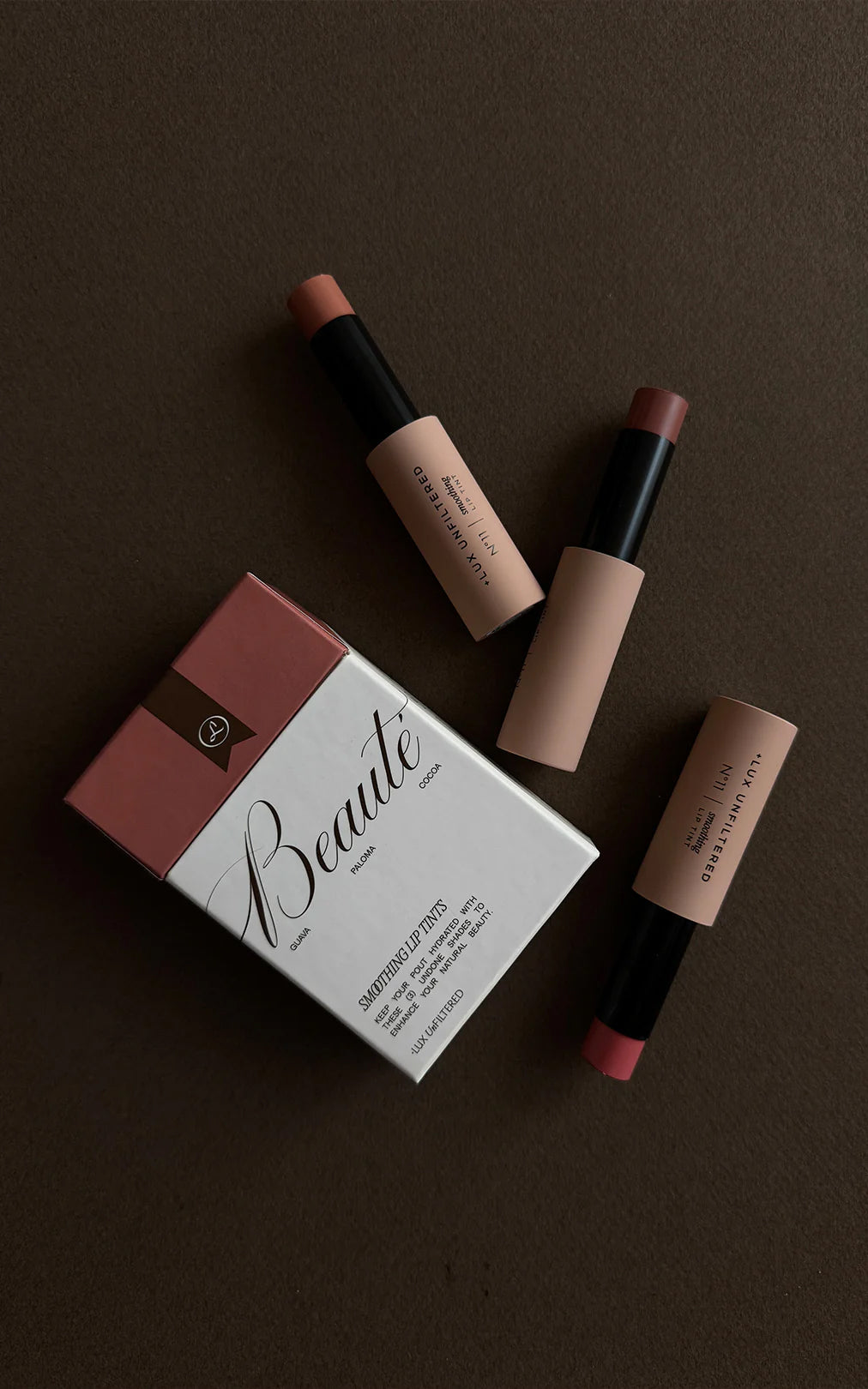 Three lip tints and a Beauté box labeled GUAVA PALOMA COCOA, SMOOTHING LIP TINTS, LUX UNFILTERED