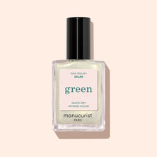 A bottle of Manucurist Solar nail polish in a shimmery pale shade with golden shimmer, black cap, and label reading 