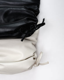 Close-up of a black and white drawstring bag on a light background