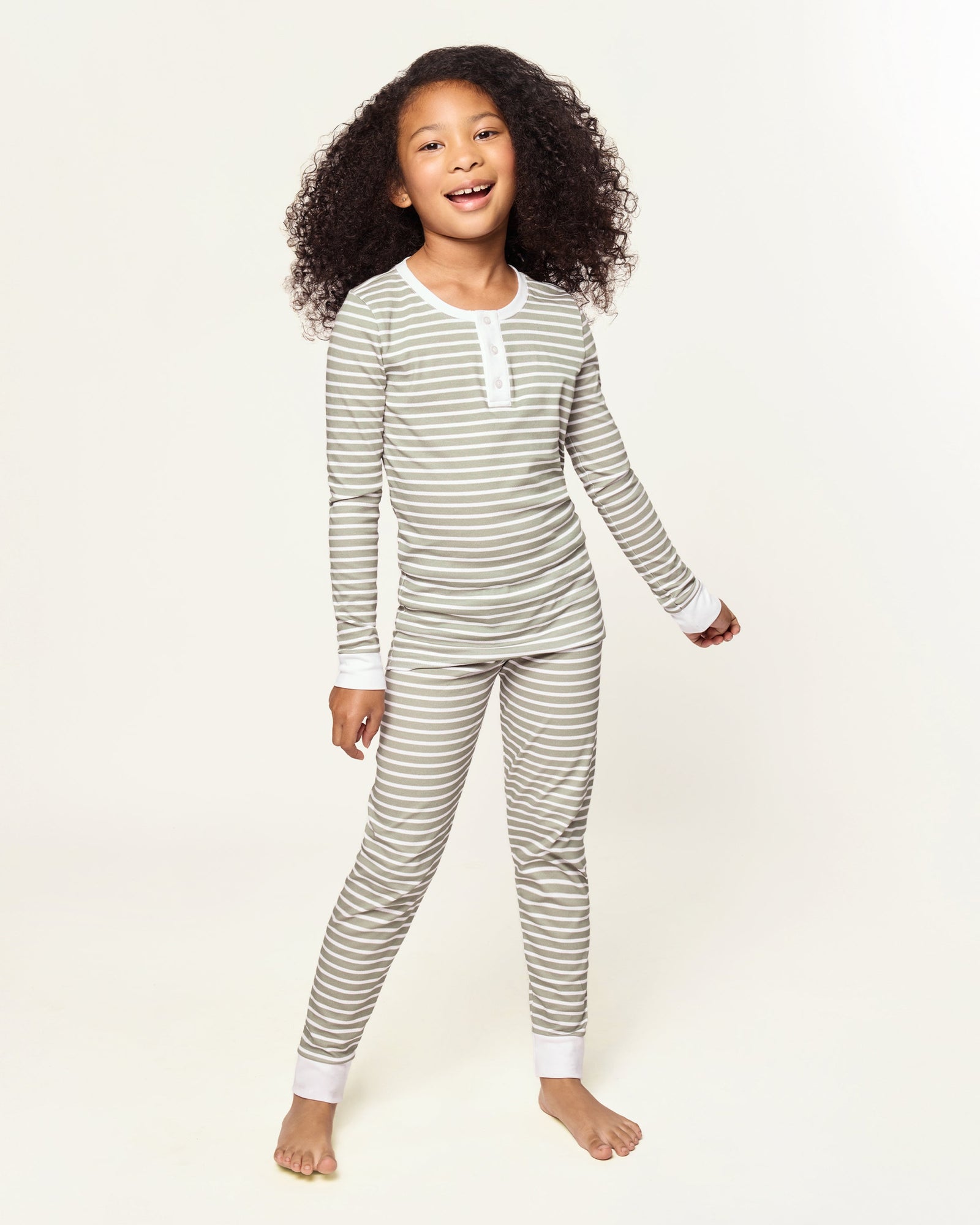 The Kid's Pima Snug Fit Pajama Set in Sage Stripe features green and white horizontal stripes, long sleeves, white cuffs at wrists and ankles, and a small button placket on the shirt. The set is displayed flat on a white background.
