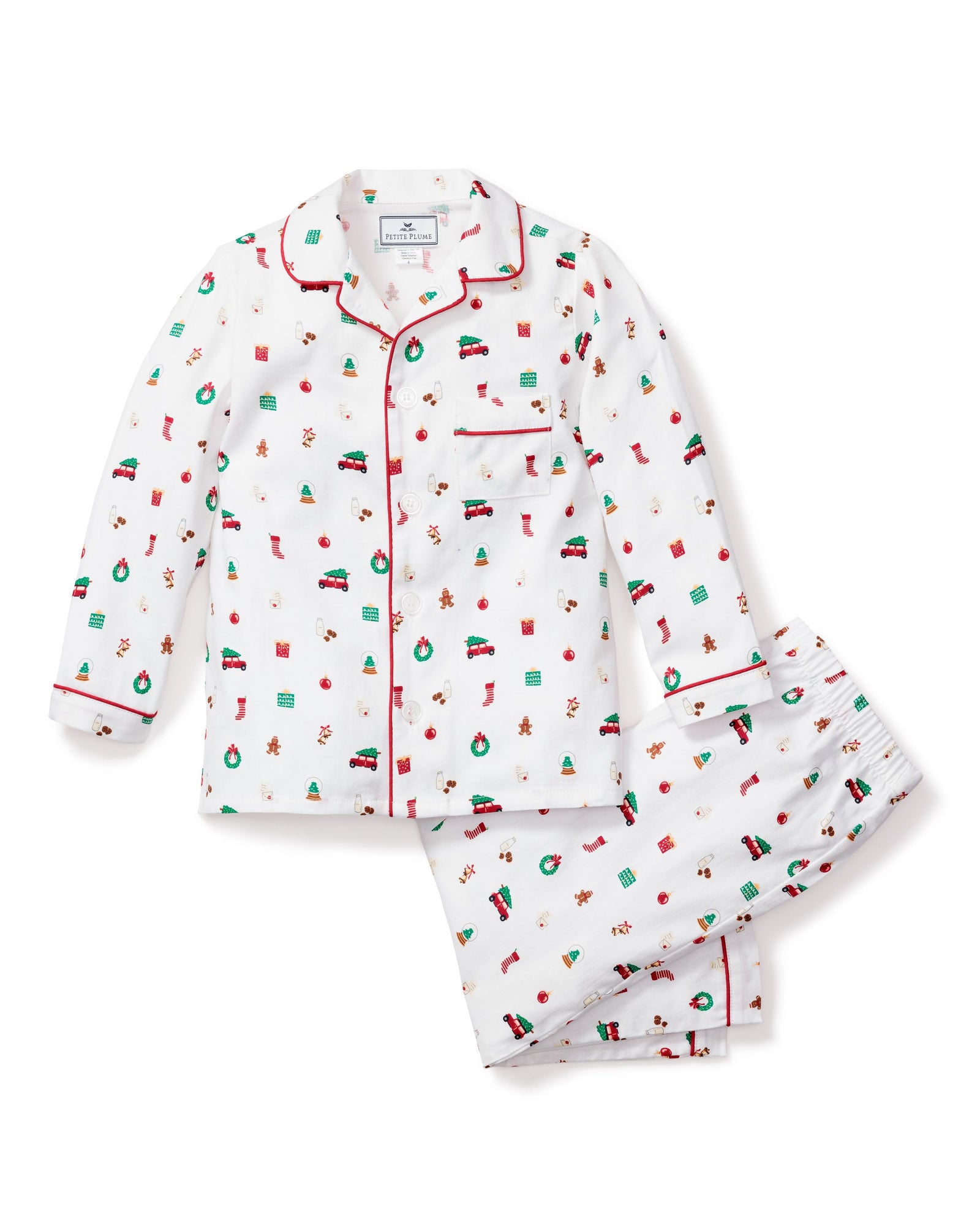 The Petite Plume Kids Twill Pajama Set in Winter Nostalgia showcases a festive winter print with red cars carrying Christmas trees, candy canes, stockings, and wreaths. This charming set includes a long-sleeve button-up top with red piping and matching pants, perfect for cozy holiday nights.