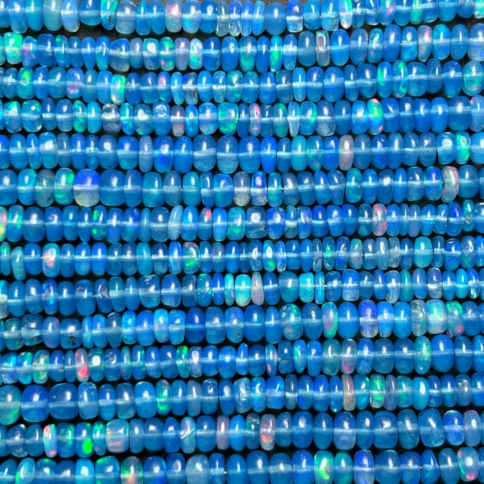 Shimmering beaded opal necklace made of smooth opals in shades of blue on a gold slim lobster clasp styled as a swatch