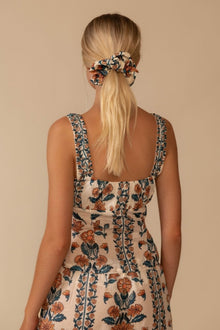 Sleeveless tank top with orange and teal floral print, square neckline, and decorative trim on straps, shown from back view.