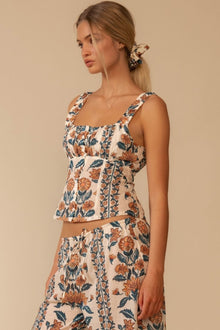 Sleeveless tank top with orange and navy floral print on cream background and square neckline.