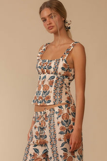 Sleeveless tank top with orange and navy floral print on cream background and ruched square neckline.